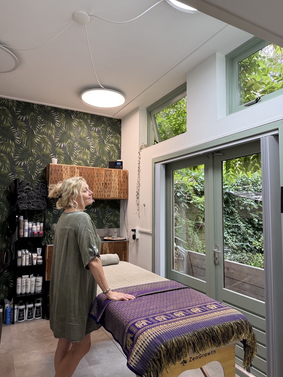 Dana naast de Reiki-behandeltafel in haar groene salonruimte in Groningen